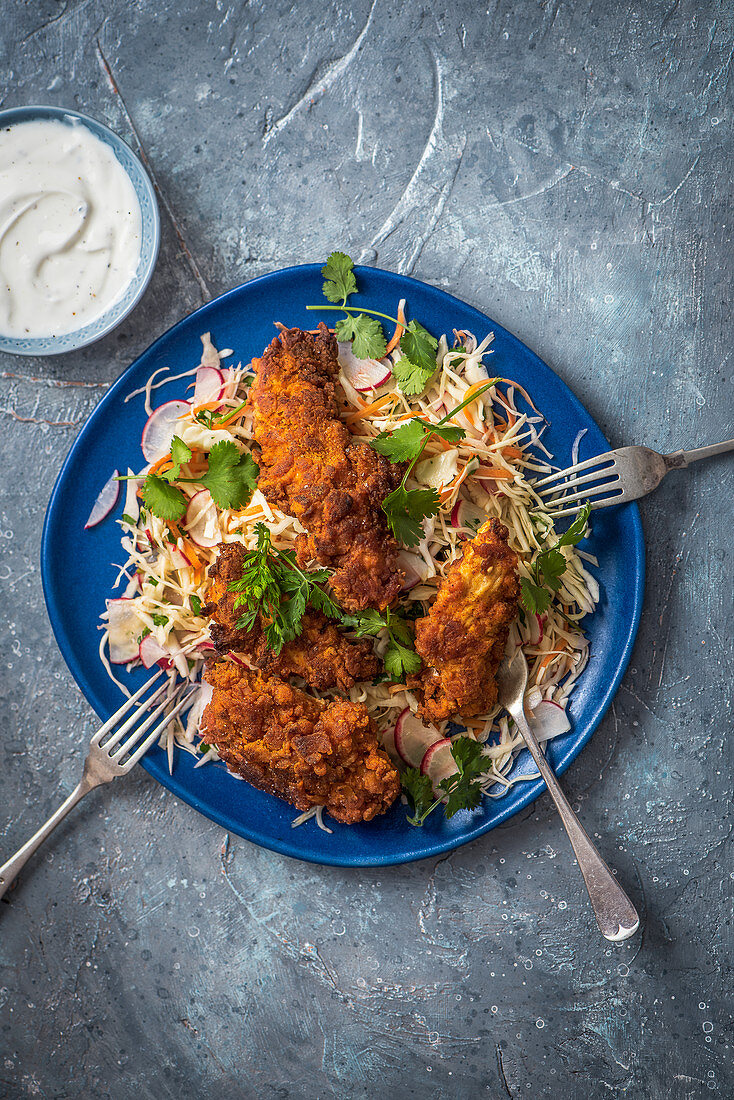 Buttermilk chicken fillets on a bed of crunchy cabbage slaw with coriander and garlic yoghurt dip