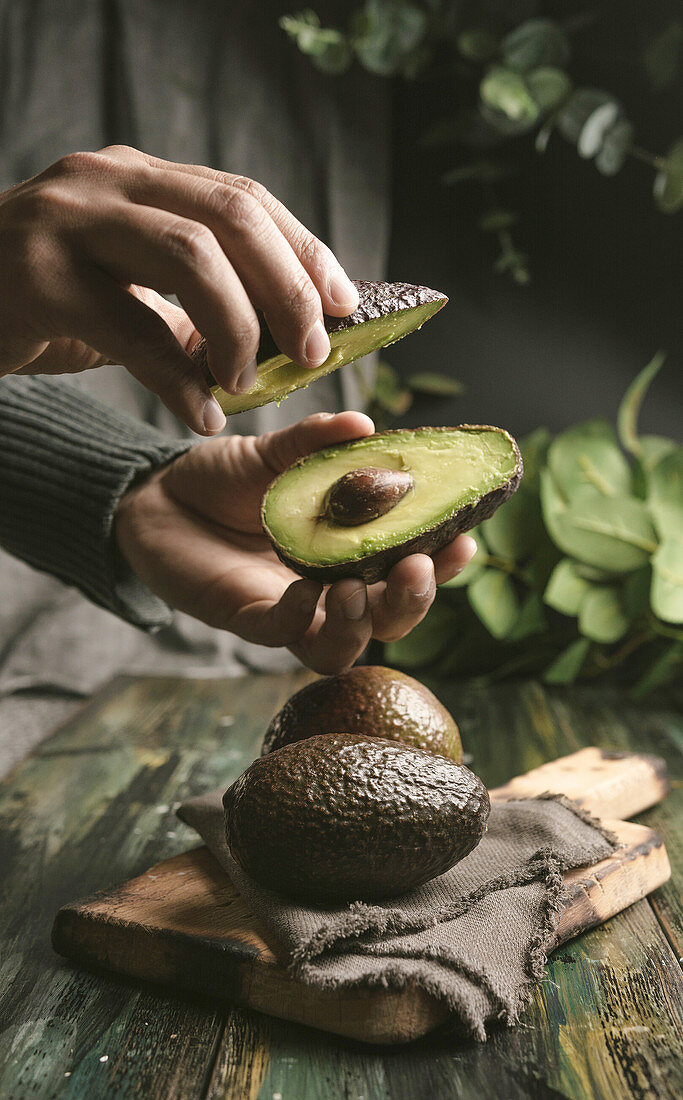 Person hands cutting avocados in half