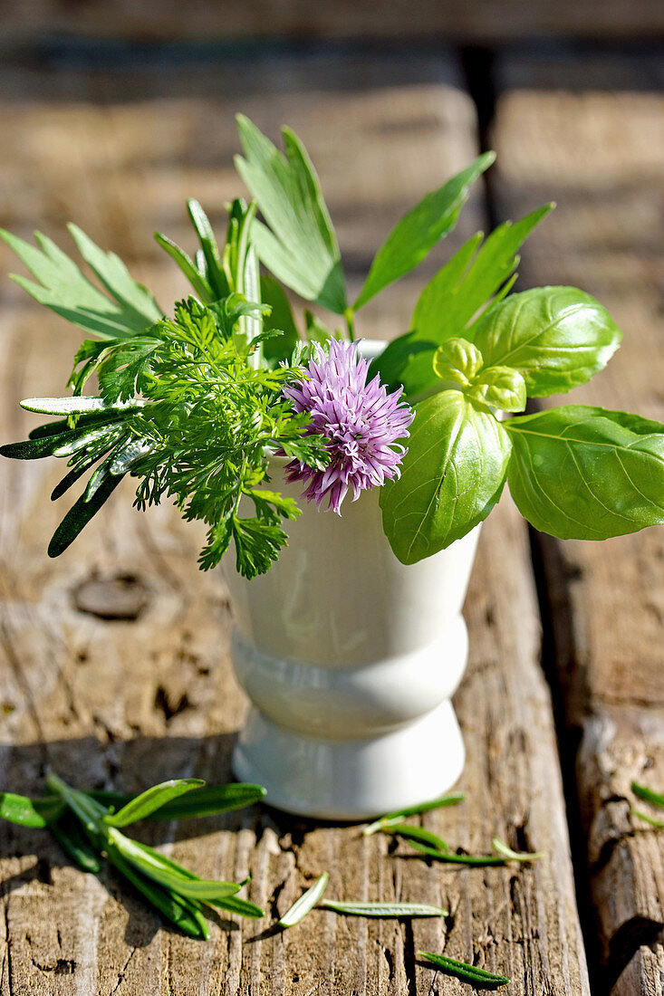 Basil, parsley and chive blossoms in a ceramic vase