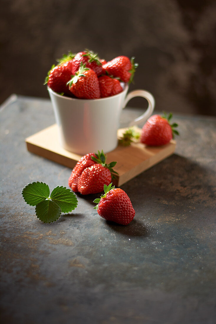 Frische Erdbeeren in Tasse auf schwarzem Blech