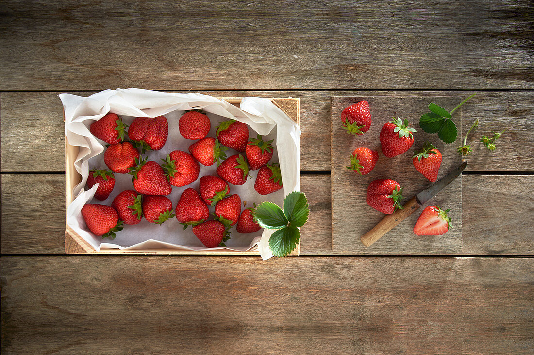 Fresh strawberries in a crate and on a wooden board