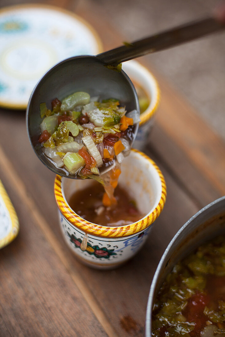 Filling small bowls with vegetable soup