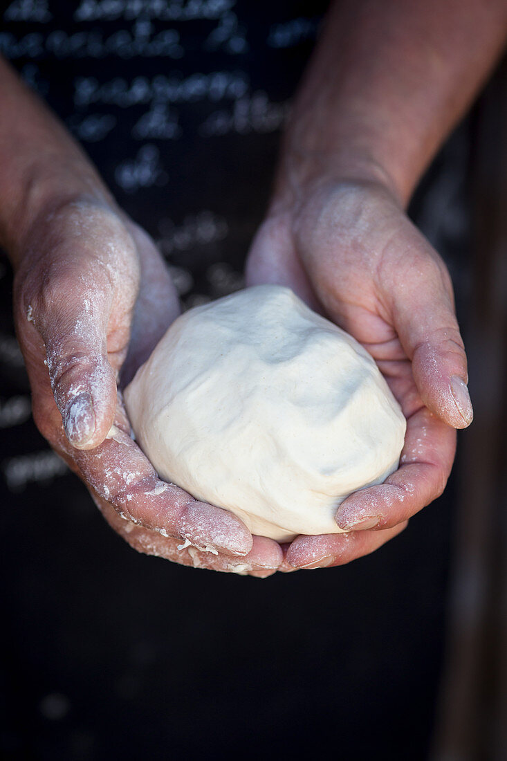 A man holding a dough ball in both hands