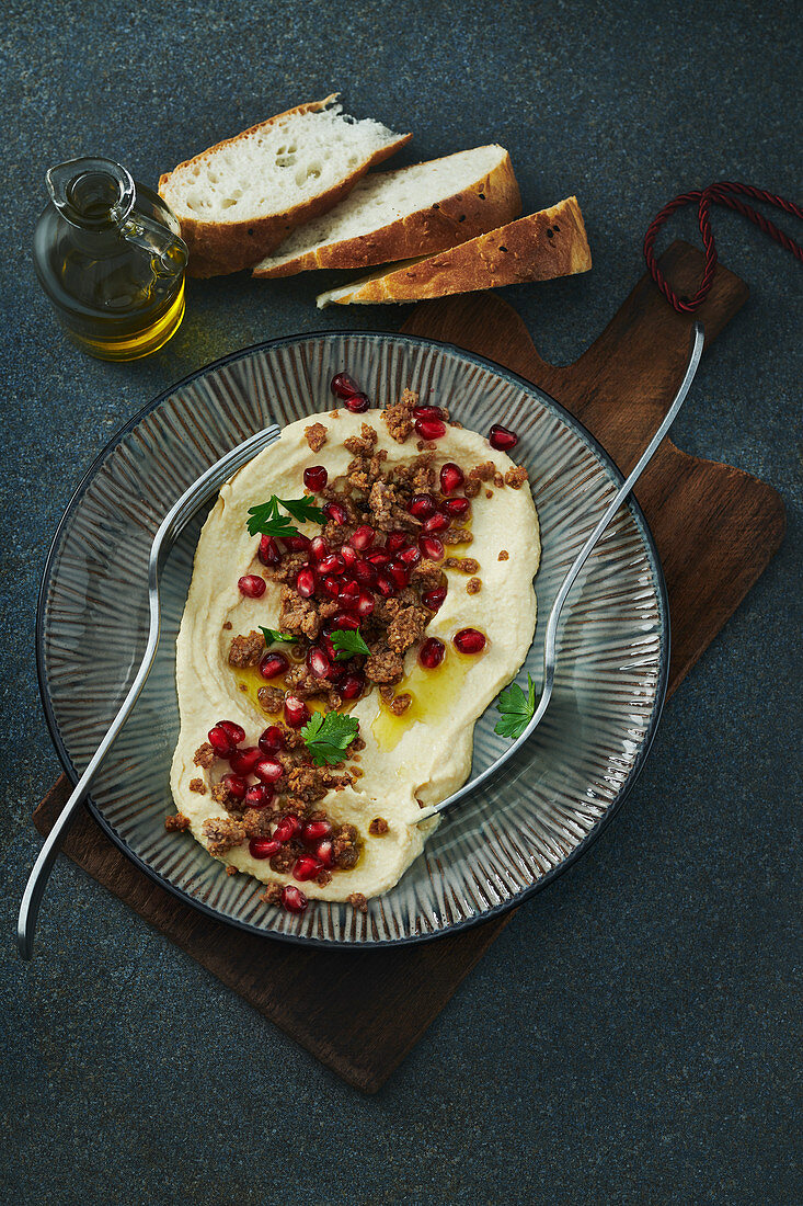 Hummus mit Granatapfelkernen, Hackfleisch und Olivenöl