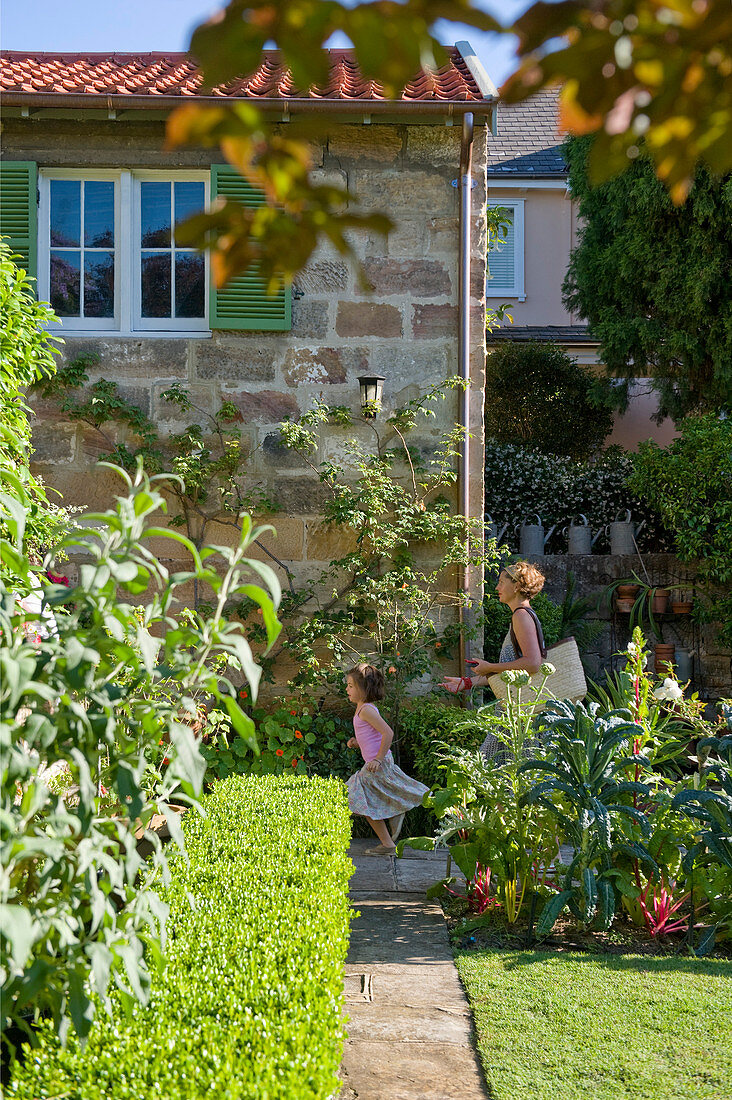 Frau und Mädchen gehen durch mediterranen Garten