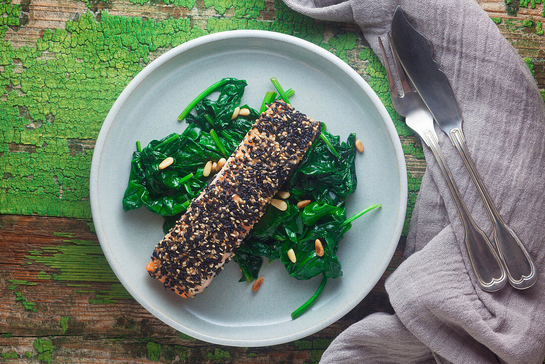 Salmon fillet coated with sesame cloves served with spinach and pine nuts