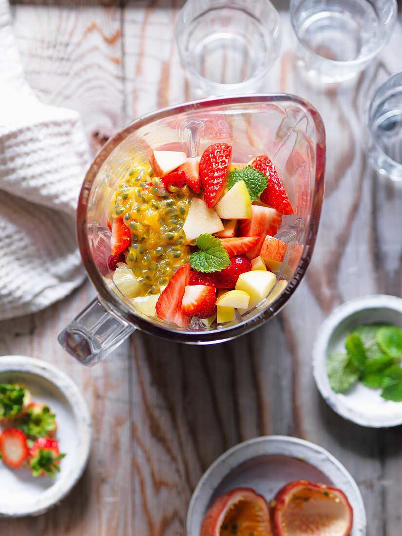 Ingredients for a smoothie (strawberries, passion fruit, lime and apple) in a blender