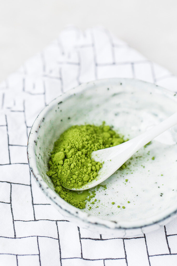 Matcha tea powder in a ceramic bowl with a spoon