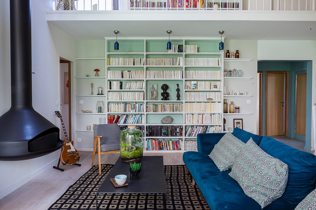 Wohnbereich in Maisonette-Wohnung mit Samtsofa, Hängekamin und Bücherwand