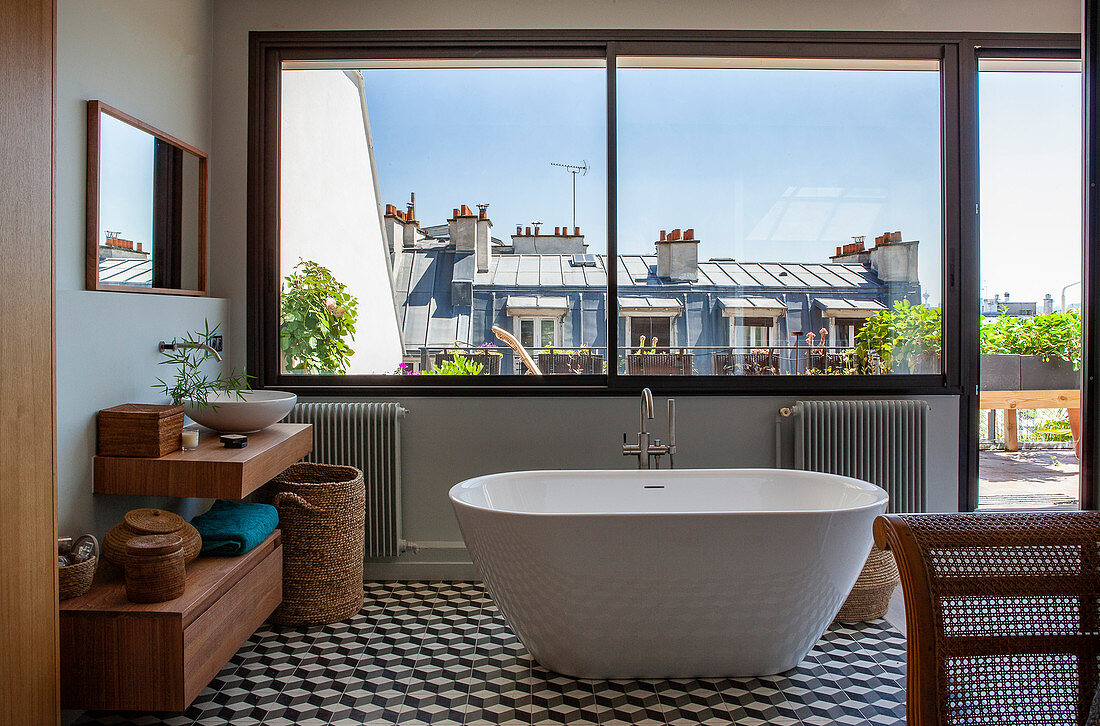 Large window, free-standing bathtub and hexagonal floor tiles in bathroom