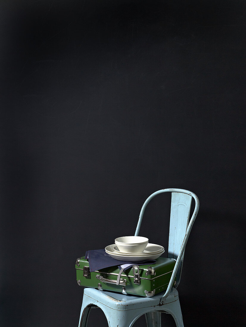 A utensils case, tea towels and white crockery on a chair