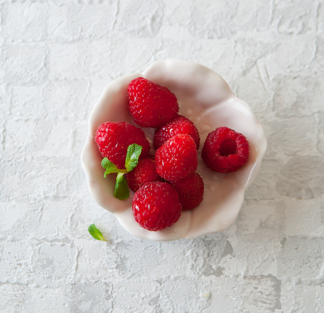 Raspberries in a bowl with a mint leaf