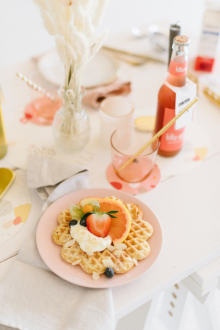 Waffel mit Früchten und Sahne auf festlich gedecktem Tisch