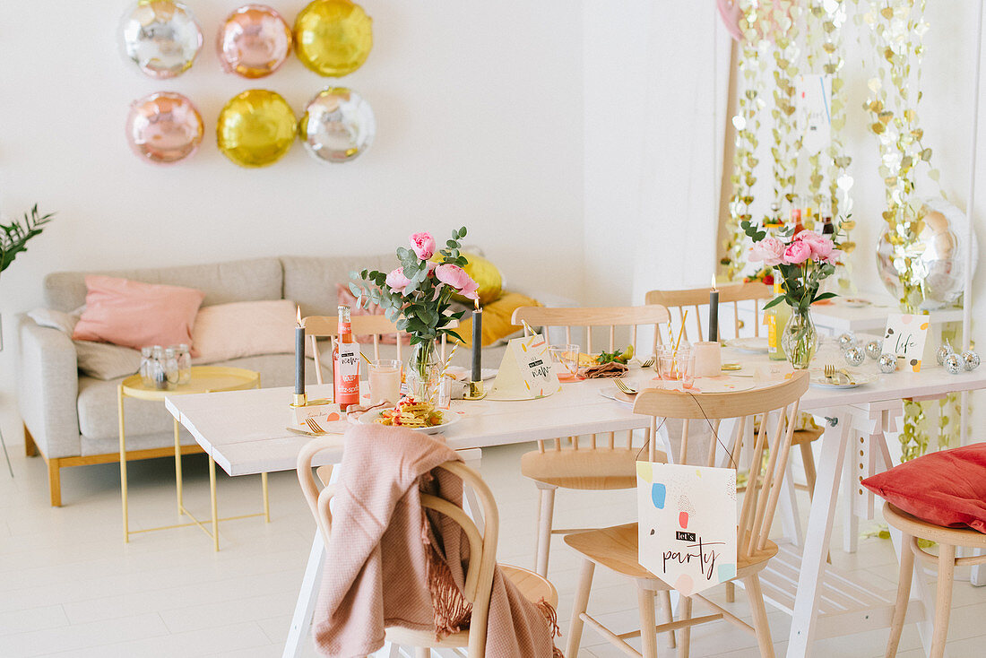 Table set for party in festively decorated living room in pastel shades