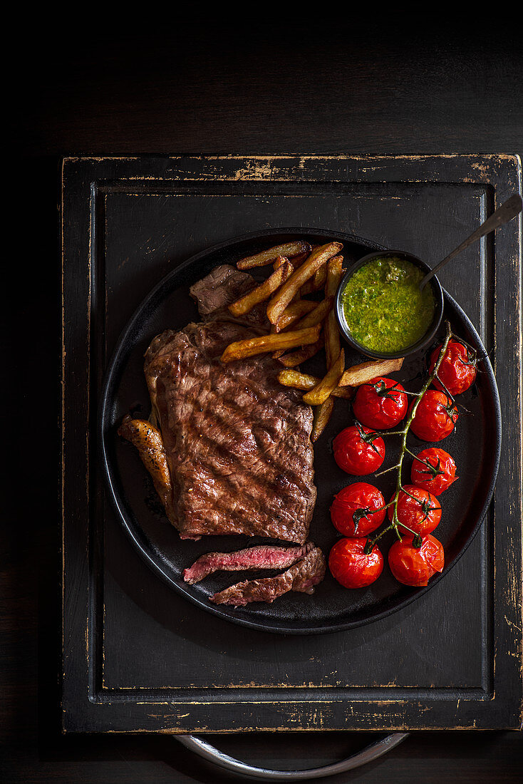 Sirloin steak with griled tomatoes, french fries and salsa verde sauce