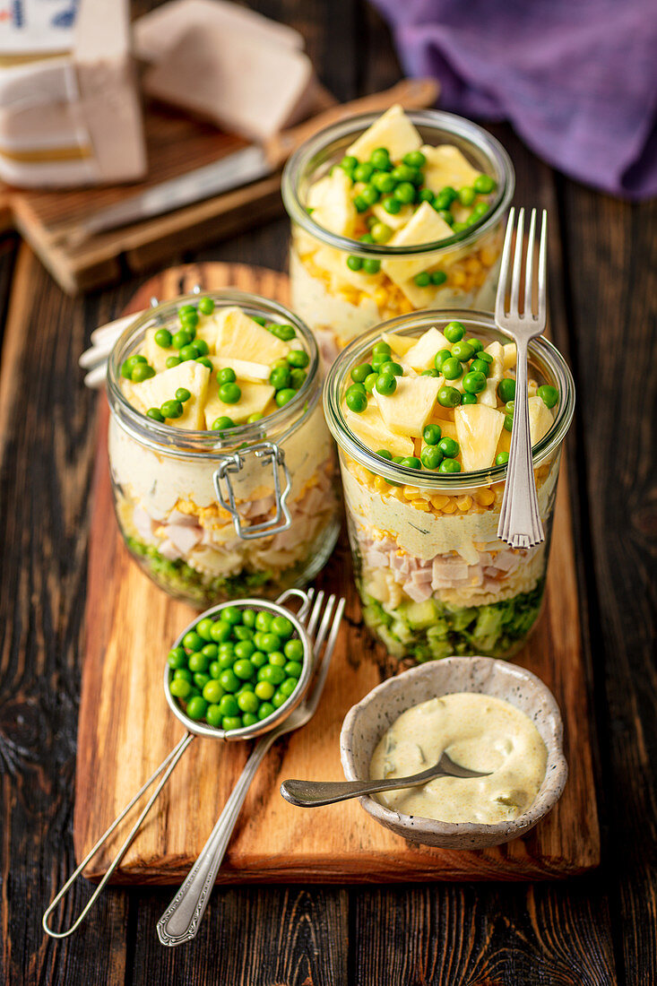 Layer salad in jar - broccoli, pasta, ham, egg, sauce, corn, pineapple and green peas