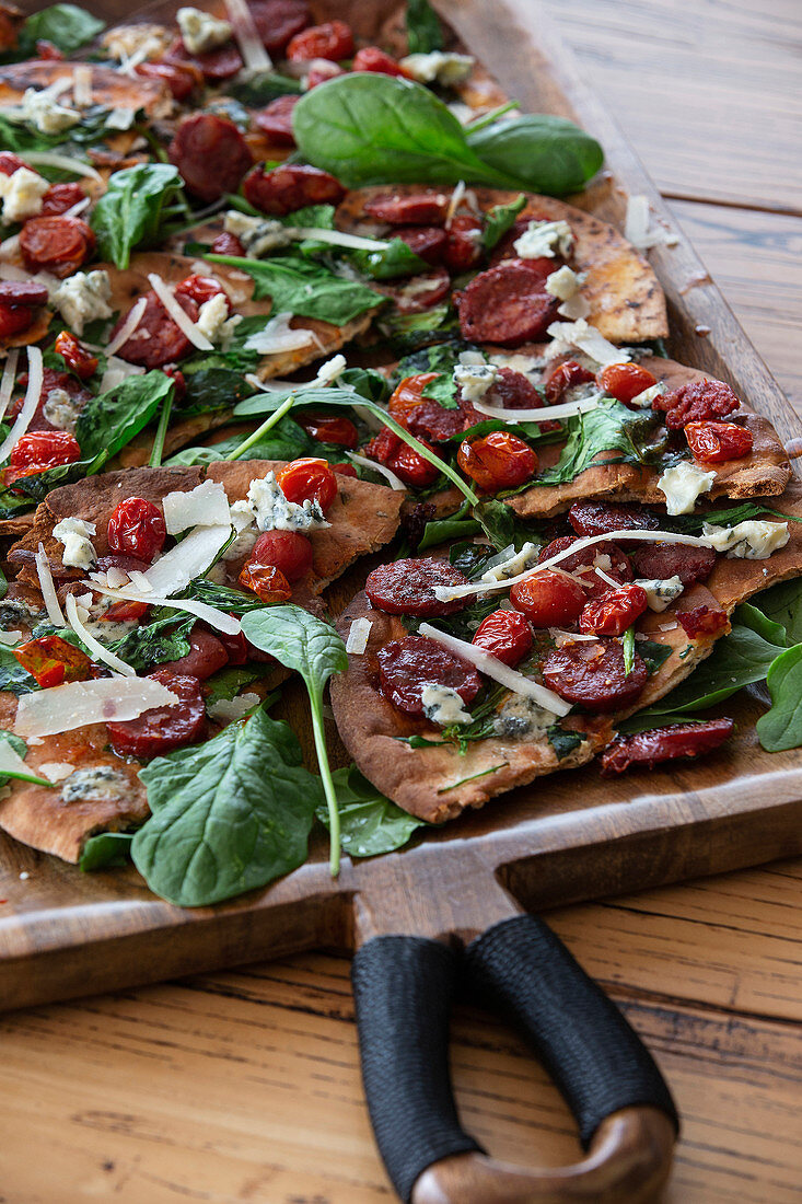 Chickpea flatbread with chorizo, spinach, cherry tomatoes and blue cheese
