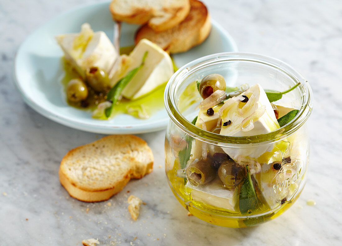 Eingelegter Rahm-Camembert mit Oliven, Zwiebel und Salbei, dazu geröstetes Baguette