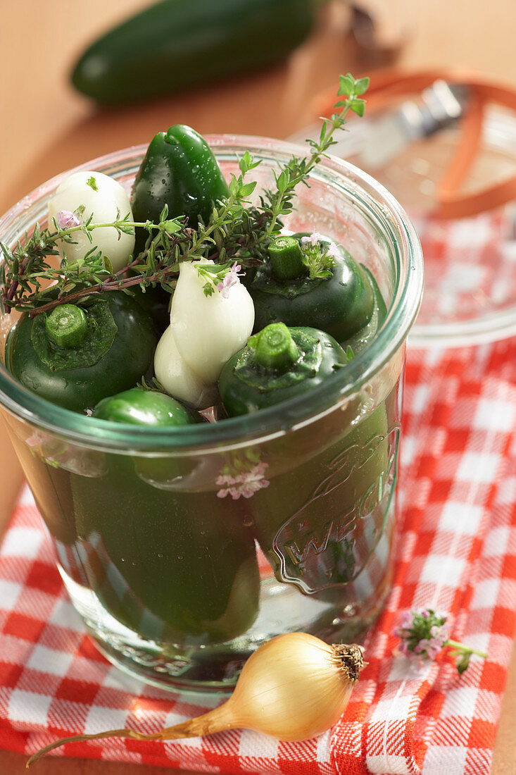 Pickled jalapenos in vinegar and sugar with pearl onions and thyme