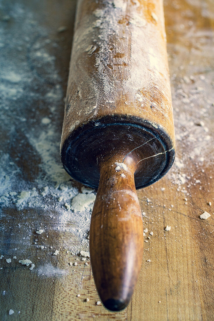 Nudelholz mit Mehl auf Holzbrett