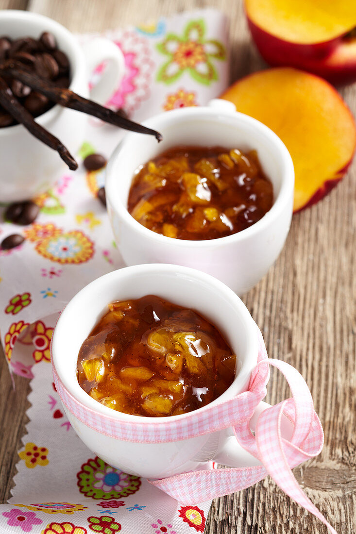 Coffee and vanilla flavoured nectarine jam in cups with a bow