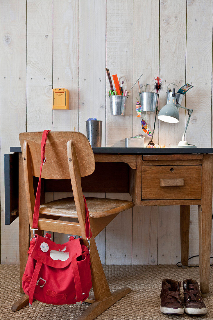 Old school chair at child's desk against board wall