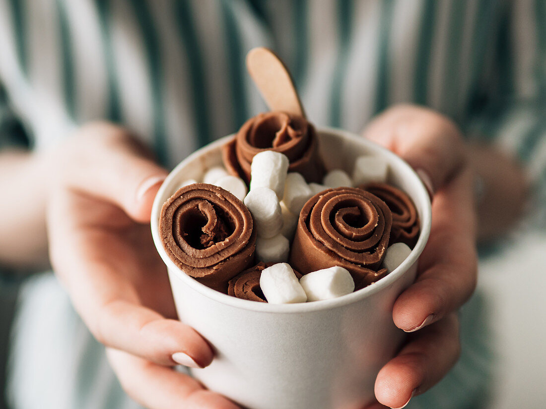 Rolled Chocolate ice cream in cone cup in woman hands