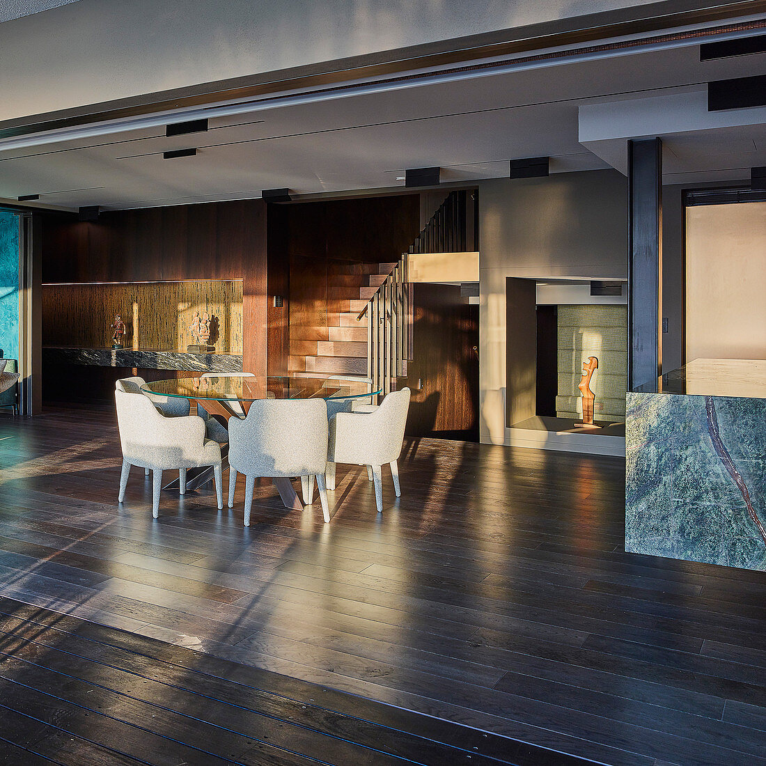 Round glass table and upholstered chairs in open-plan interior