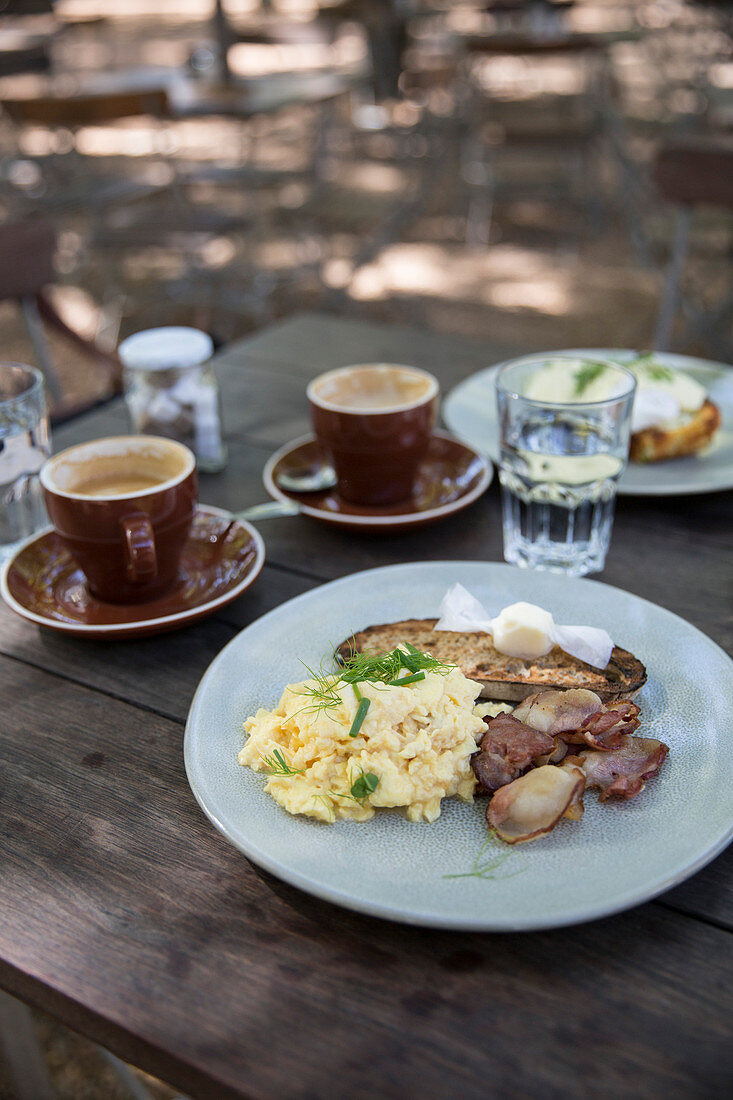 A sumer breakfast al fresco with scrambled eggs, bacon and cappuccinos