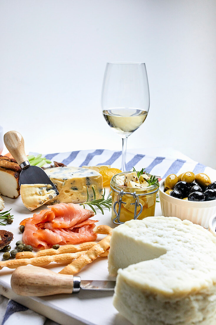 Mediterrane Vorspeisenplatte mit Käse, Fisch, Oliven und Weißwein