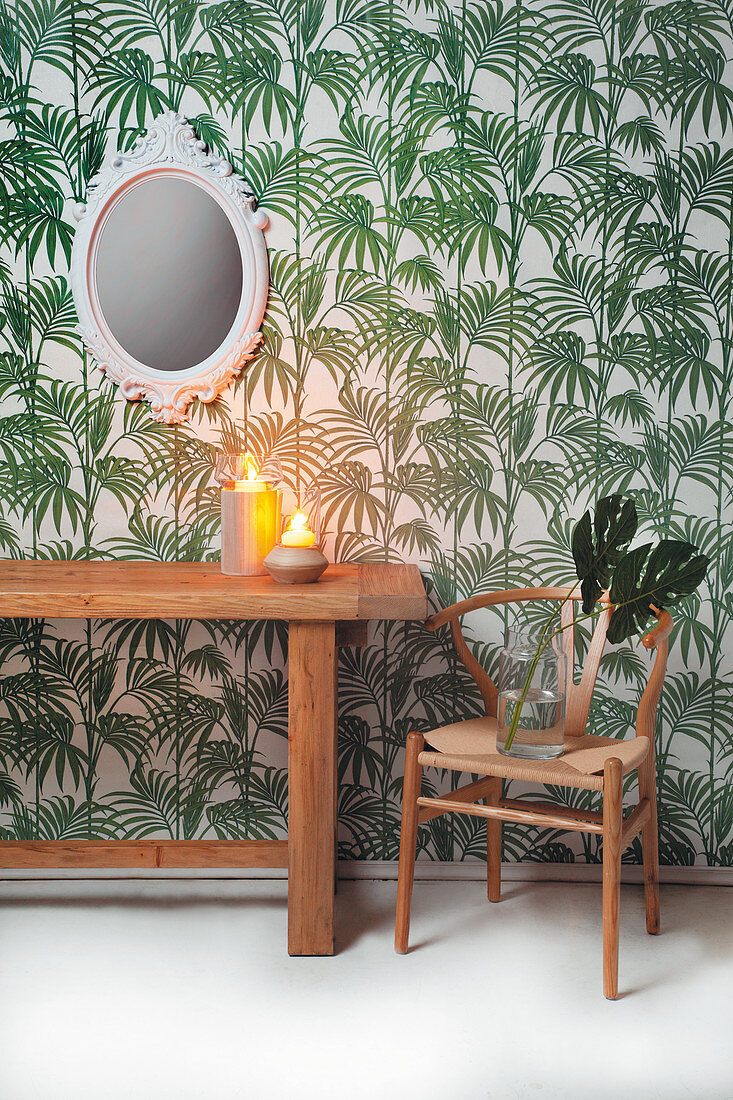 Wooden table and classic chair against leaf-patterned wallpaper
