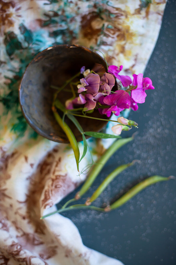 Pink sweet peas in bowl on floral cloth