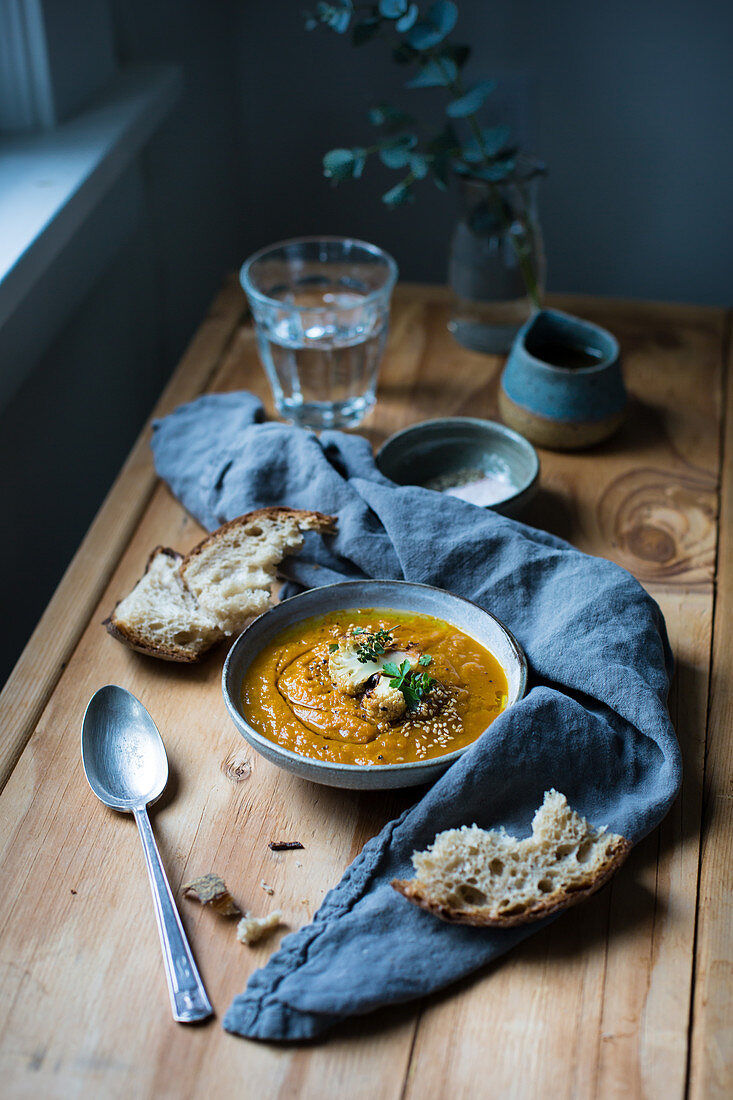 Karottensuppe mit geröstetem Blumenkohl serviert mit Brot