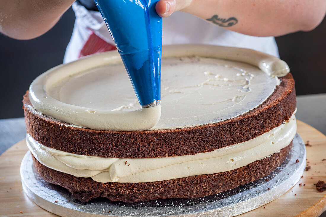 Pipe vanilla buttercream onto chocolate base of wedding cake