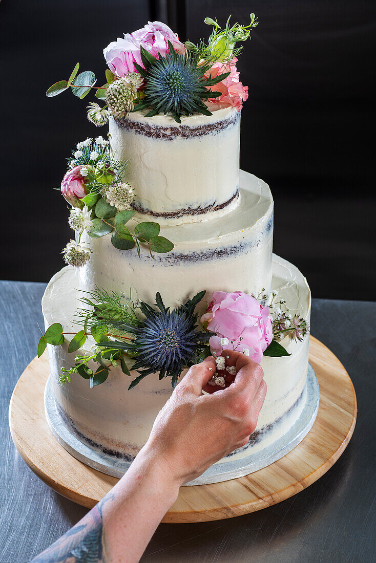 Dreistöckige Hochzeitstorte mit Schokoladenböden, Vanillebuttercreme, Himbeerfüllung und Blumendeko