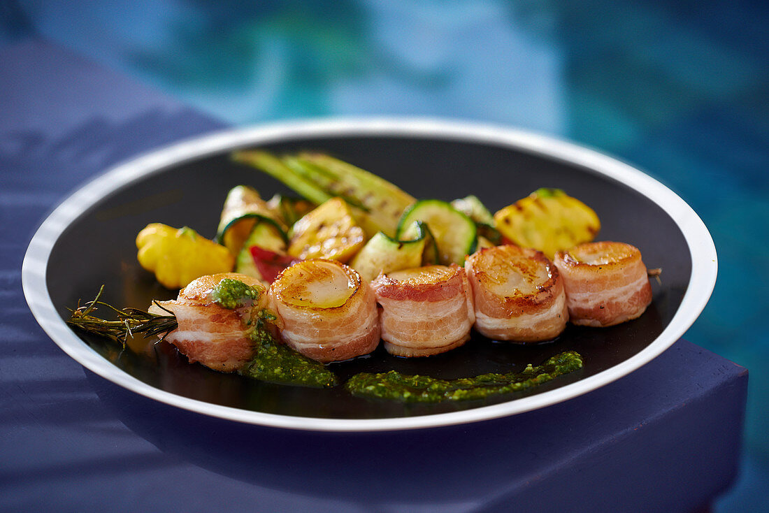 Scallops wrapped in bacon with vegetables