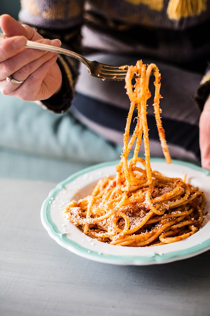 Person isst Spaghetti mit Tomatensauce