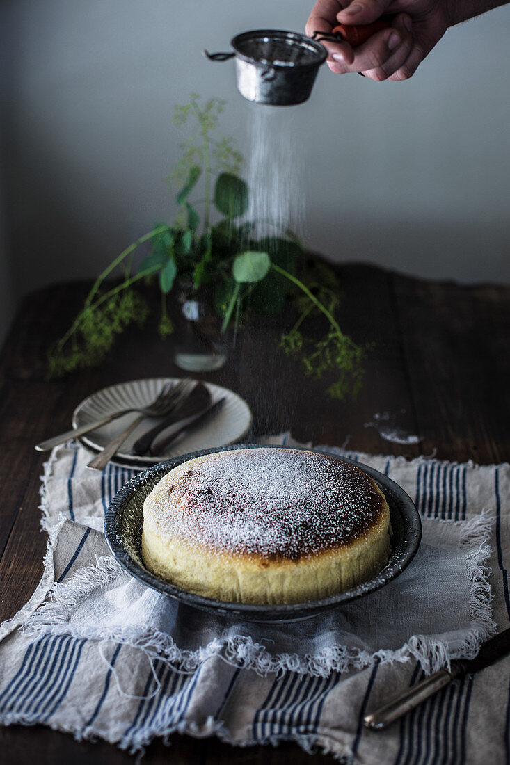 Japanischer Käsekuchen wird mit Puderzucker besiebt