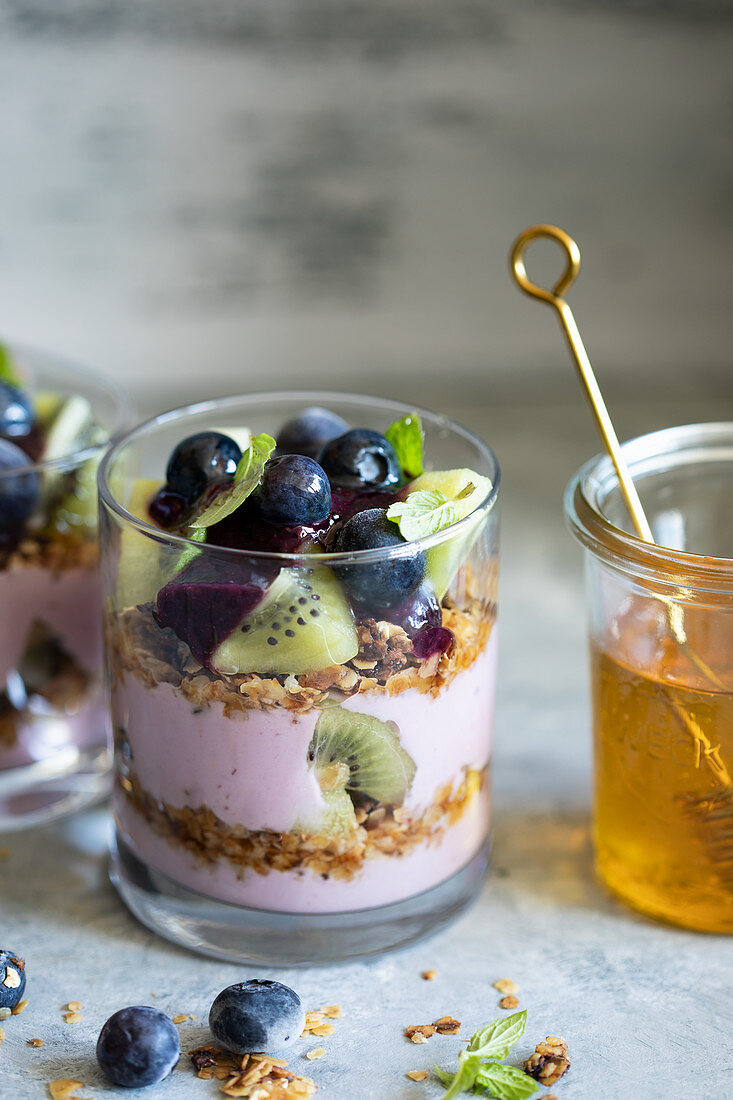 A layered dessert with blueberry yoghurt, crunchy muesli and kiwi