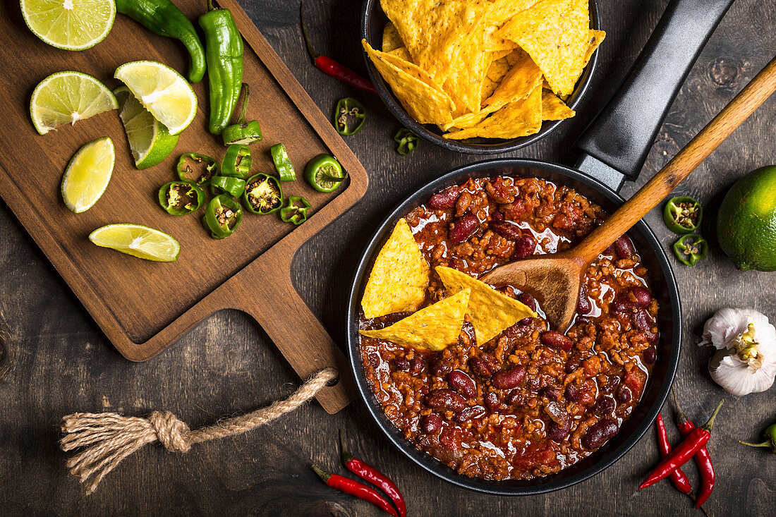 Chili con carne in frying pan on dark wooden background