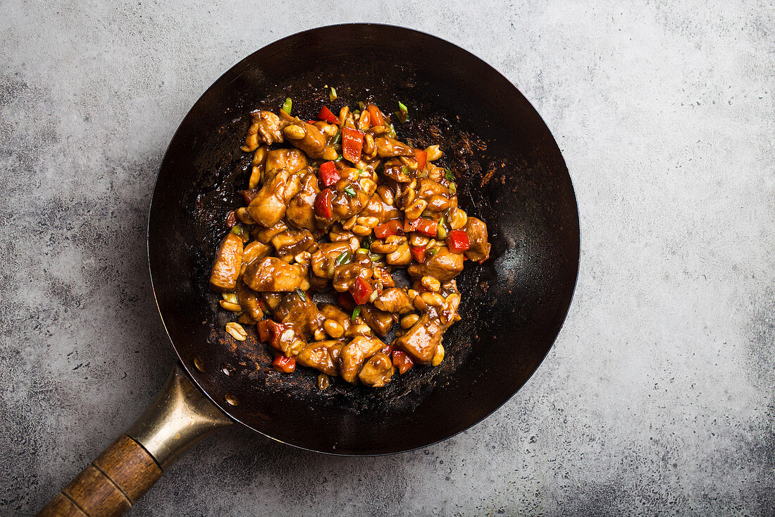 Top view of Kung Pao chicken, stir-fried Chinese traditional dish with chicken, peanuts, vegetables, chili peppers in a wok pan