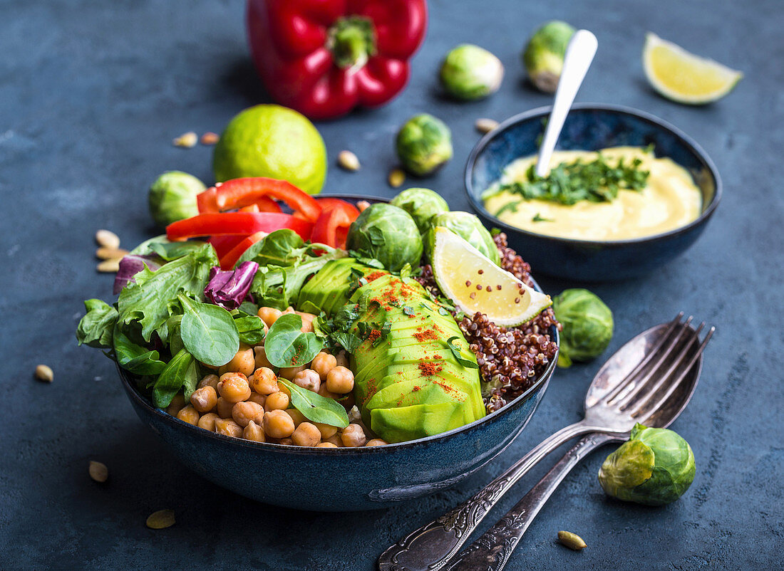 Buddha bowl with chickpea, avocado, quinoa seeds, red bell pepper, fresh spinach, brussels sprout, lime mix