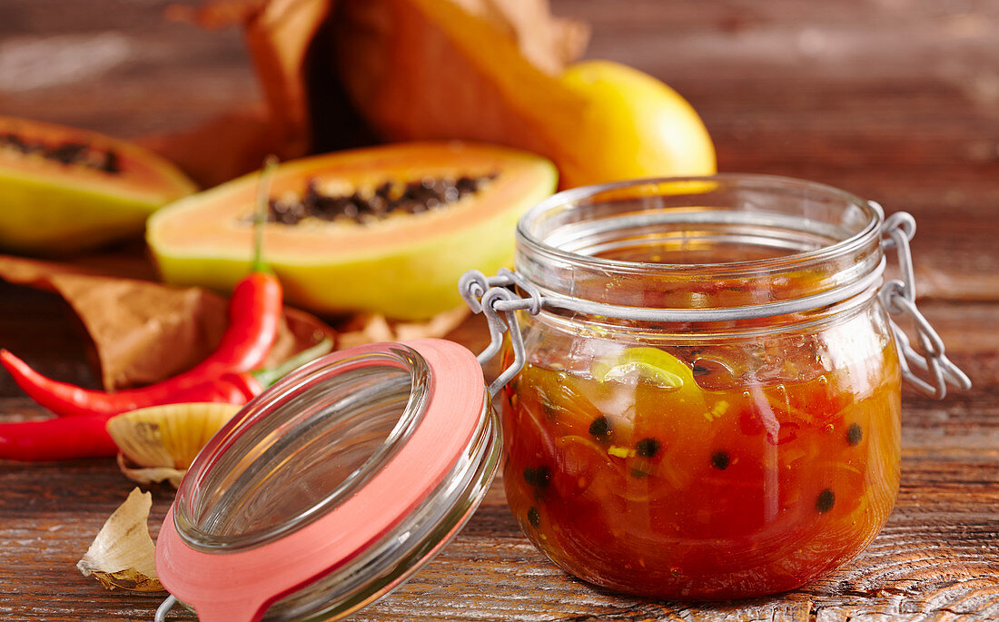 Papaya and orange chutney with curry and hot peppers in a jar
