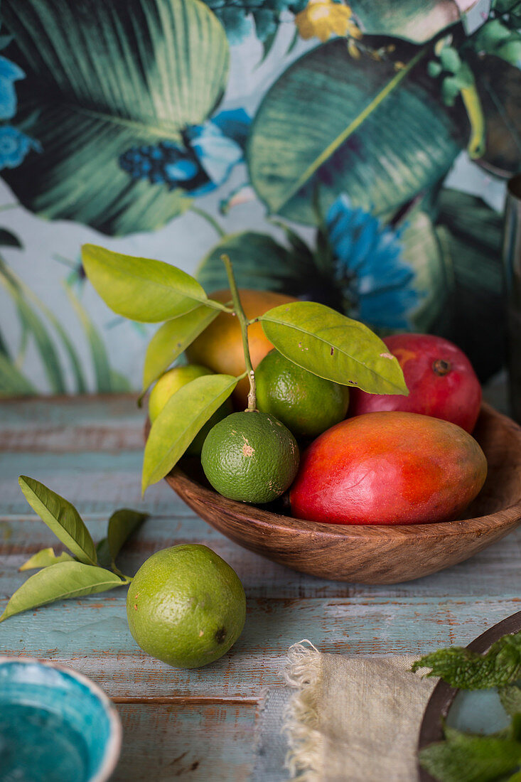 Mango and limes in a wooden bowl