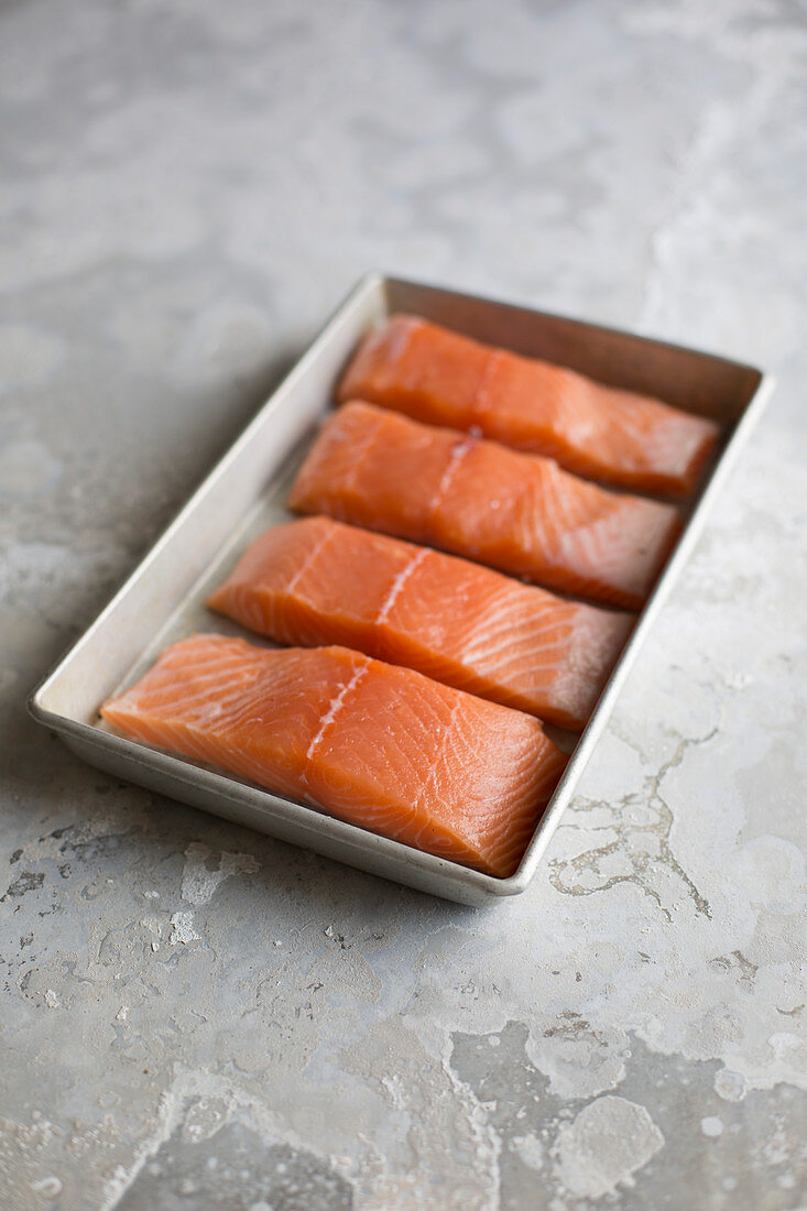 Raw salmon fillets in a tin bowl