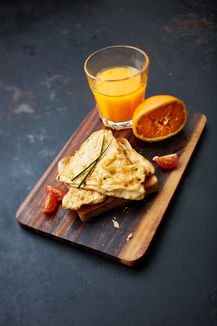 Breakfast with scrambled eggs on toast and a glass of freshly pressed orange juice