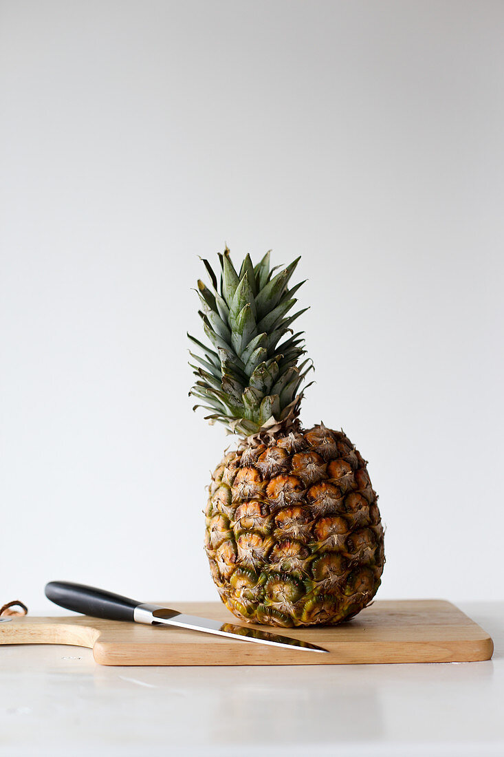 Pineapple on a cutting board with a knife