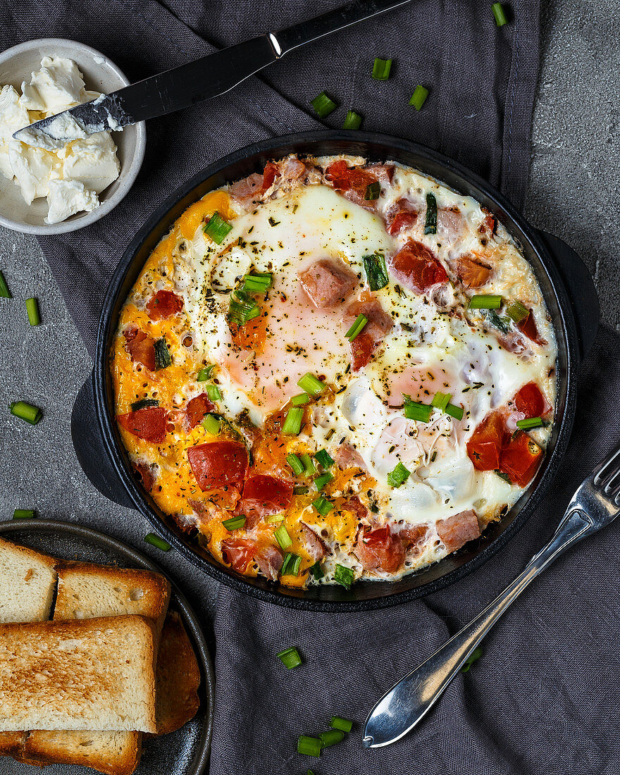 Roasted eggs with ham, tomatoes and green onions