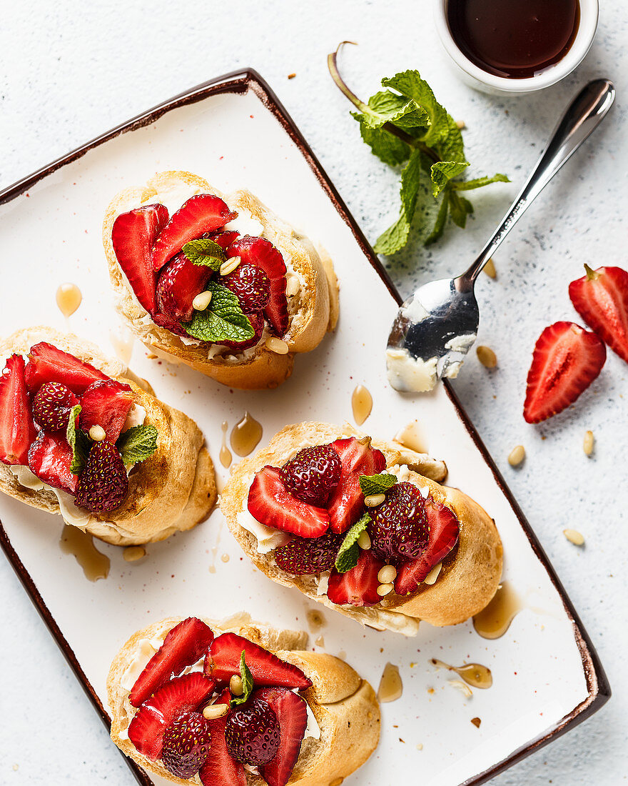 Bruschettas with mascarpone cheese, strawberries pine nuts and syrup