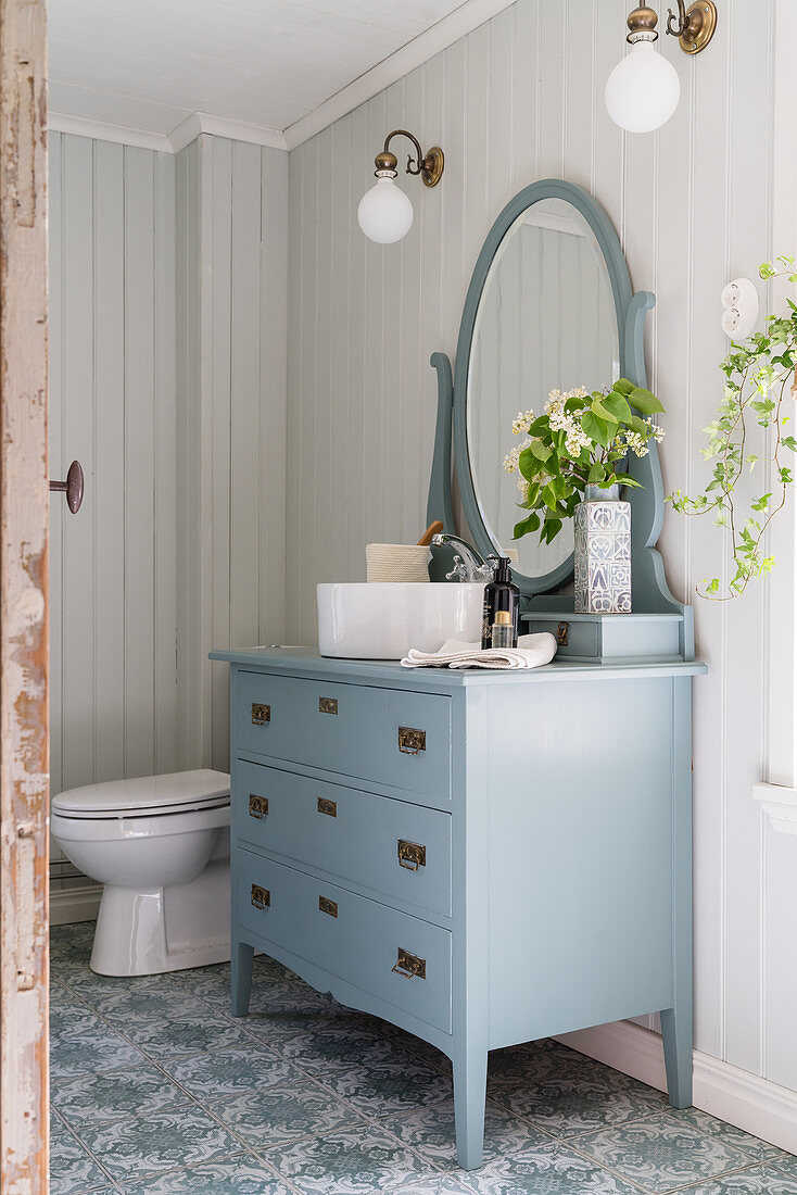Washstand made from blue chest of drawers with mirror on top in country-house-style bathroom